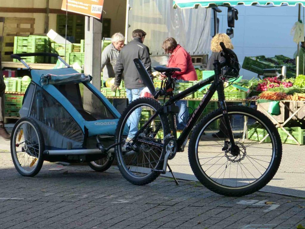 A blue bike trailer and road bike upright